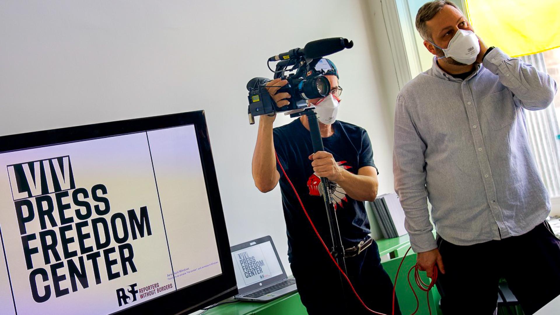 Zwei Menschen stehen vor einem Bildschirm mit der Aufschrift "Lviv Press Freedom Center"