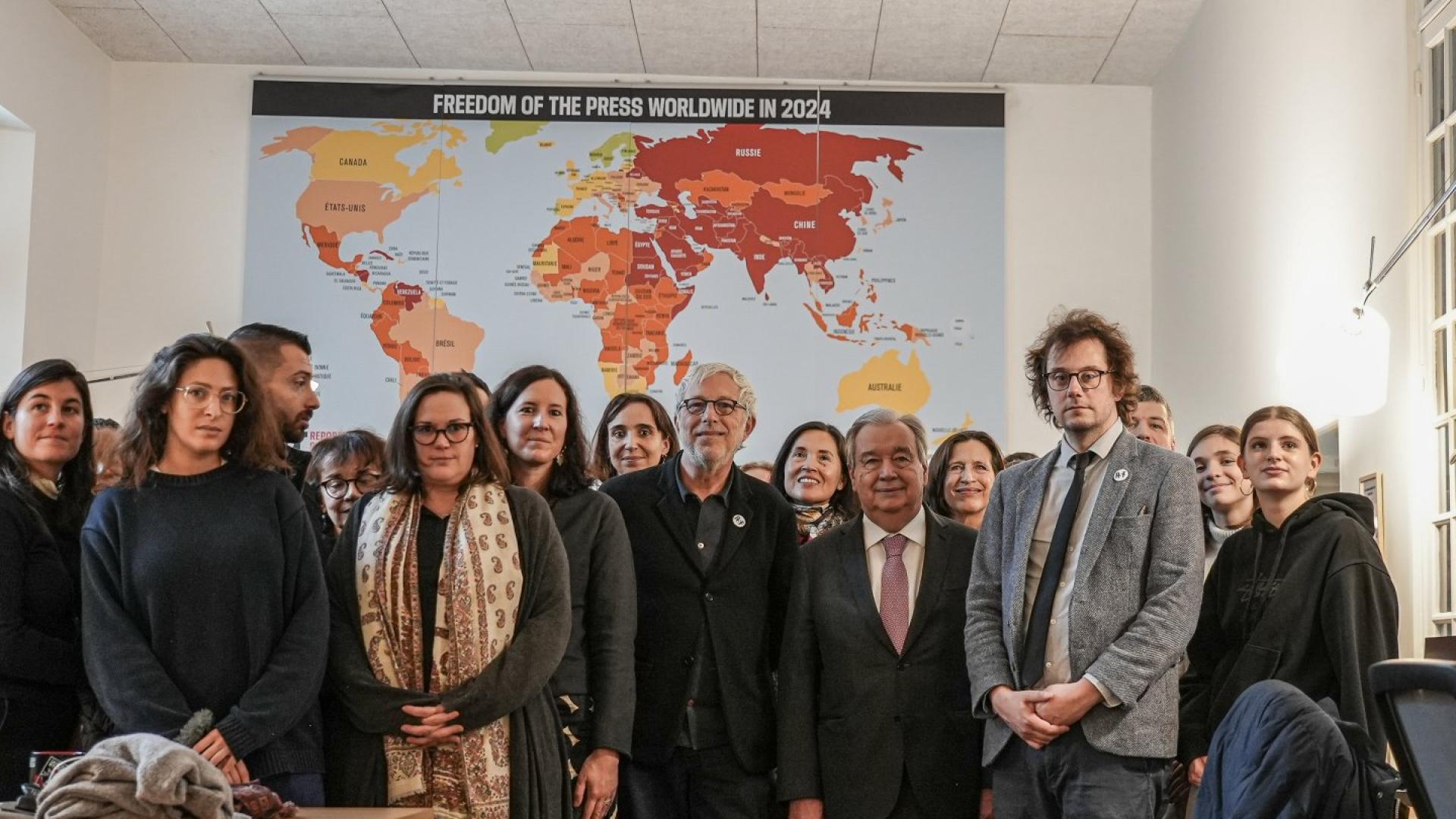 Der UN-Generalsekretär António Guterres gemeinsam mit Teilen des RSF-Teams in Paris vor der Weltkarte der Pressefreiheit 2024