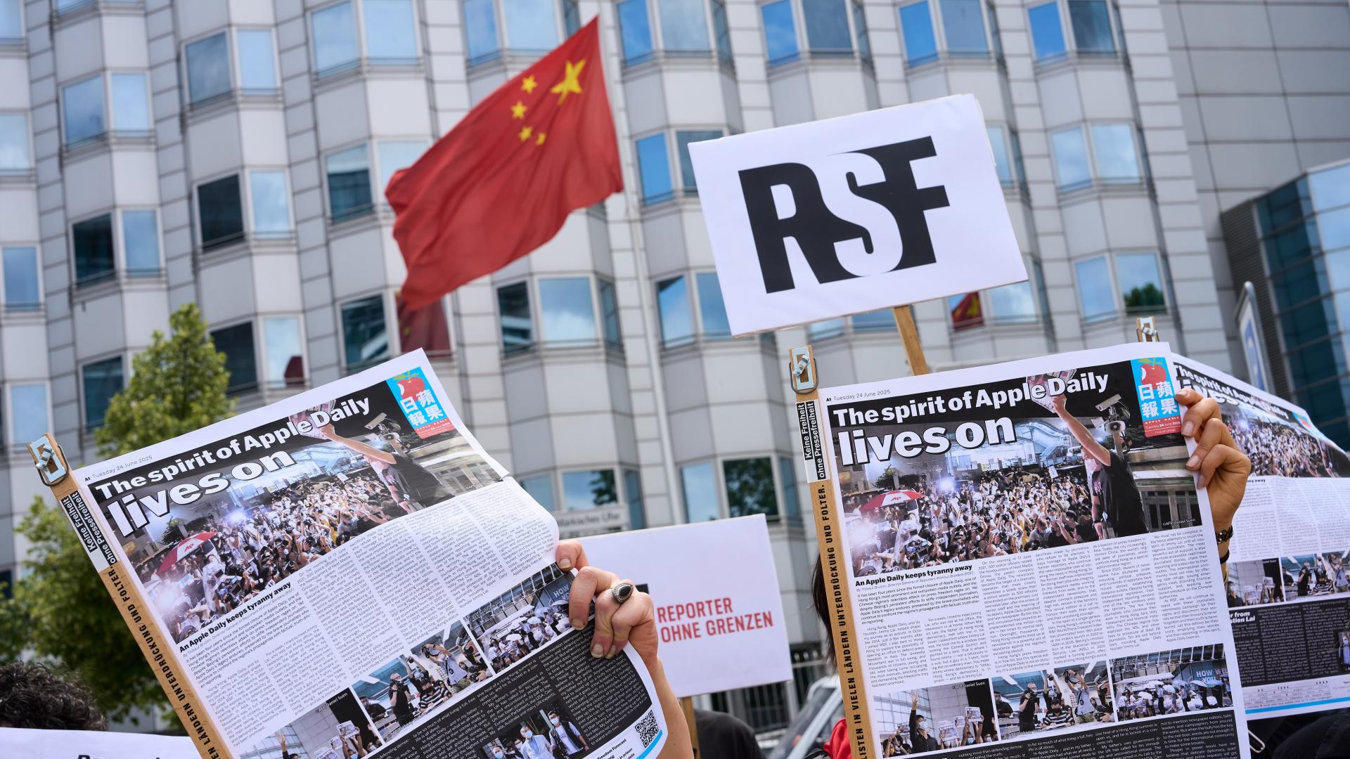 Vor der chinesischen Botschaft in Berlin wird die Sonderausgabe der "Apple daily" gemeinsam mit dem RSF-Logo hochgehalten