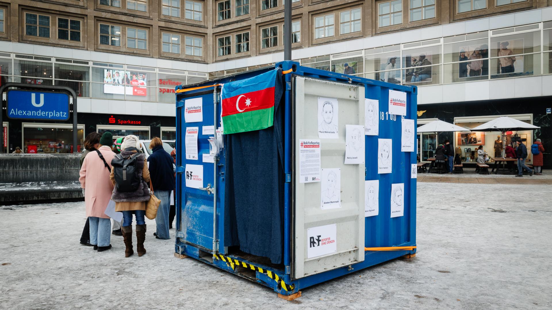 Außenansicht auf blauen Container mit Aserbaidschan-Flagge und Illustrationen von aserbaidschanischen Inhaftierten