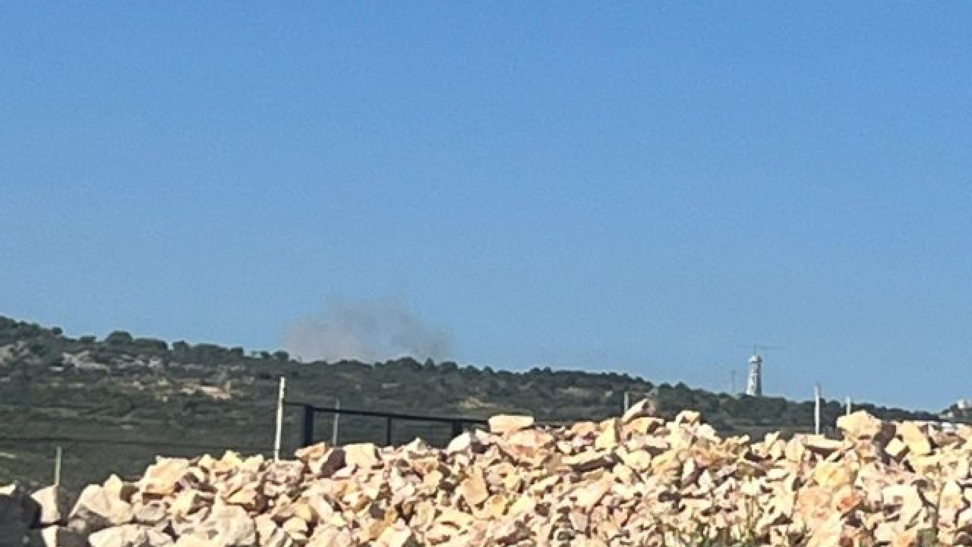 Das Bild zeigt eine steinige Landschaft. In der Ferne sieht man eine Rauchwolke, von dem Angriff. 