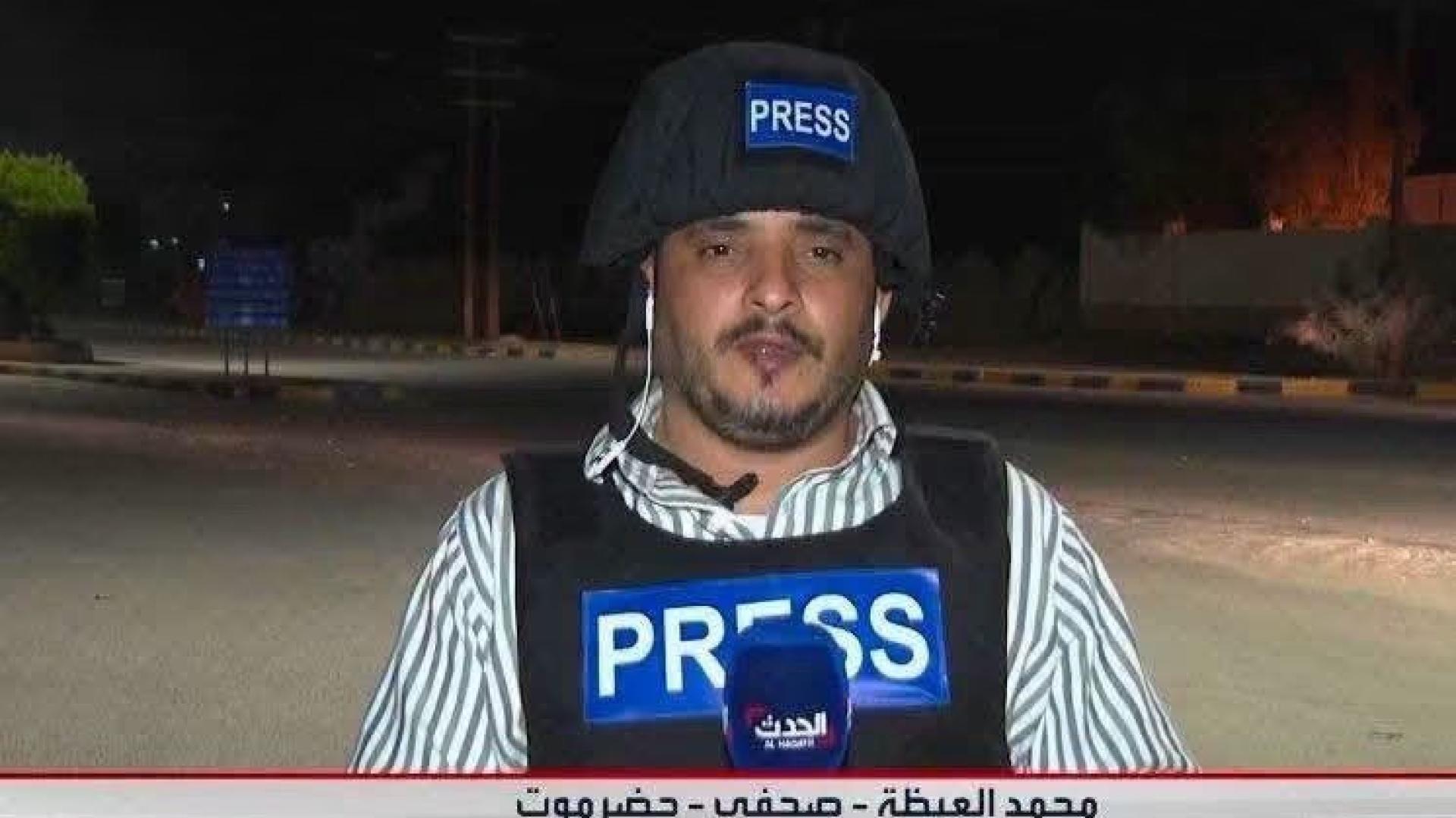 Screenshot eines Fernsehbeitrags. Ein Mann steht mit Helm und Weste mit der Aufschrift "Presse" auf einer Straße. 