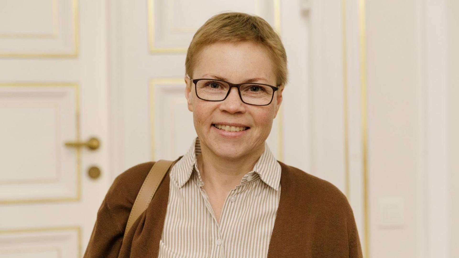 Porträt der belarusischen Journalistin Maryna Solatawa, eine Frau mittleren Alters mit kurzen blonden Haaren und einer schwarzen Brille, vor einem hellen Hintergrund.